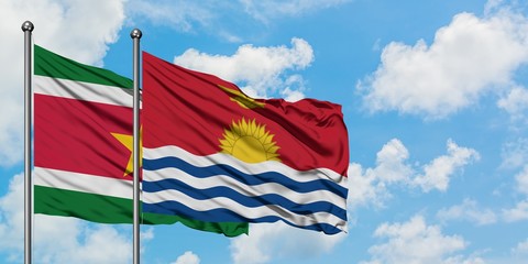 Suriname and Kiribati flag waving in the wind against white cloudy blue sky together. Diplomacy concept, international relations.