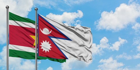 Suriname and Nepal flag waving in the wind against white cloudy blue sky together. Diplomacy concept, international relations.