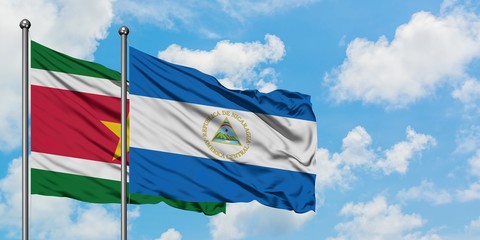 Suriname and Nicaragua flag waving in the wind against white cloudy blue sky together. Diplomacy concept, international relations.