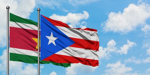 Suriname and Puerto Rico flag waving in the wind against white cloudy blue sky together. Diplomacy concept, international relations.
