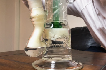 Smoking marijuana through bong. a Cannabis smoking hookah system.