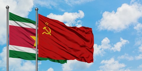 Suriname and Soviet Union flag waving in the wind against white cloudy blue sky together. Diplomacy concept, international relations.