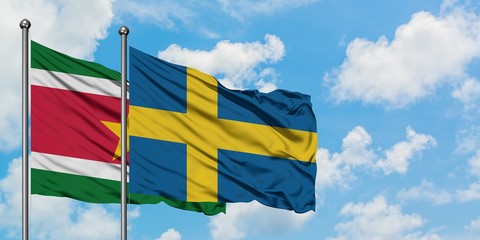Suriname and Sweden flag waving in the wind against white cloudy blue sky together. Diplomacy concept, international relations.