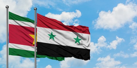 Suriname and Syria flag waving in the wind against white cloudy blue sky together. Diplomacy...