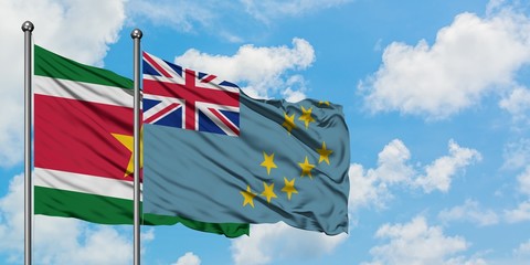 Suriname and Tuvalu flag waving in the wind against white cloudy blue sky together. Diplomacy...