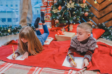 Two sweet children are writing message to Santa Claus.