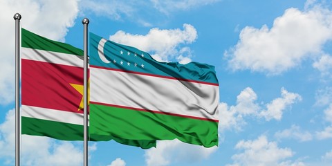 Suriname and Uzbekistan flag waving in the wind against white cloudy blue sky together. Diplomacy concept, international relations.
