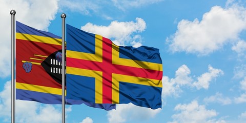 Swaziland and Aland Islands flag waving in the wind against white cloudy blue sky together....