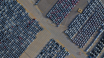 Aerial drone top down photo of new cars lined up in automobile port terminal for import and export