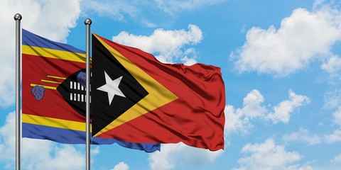 Swaziland and East Timor flag waving in the wind against white cloudy blue sky together. Diplomacy concept, international relations.