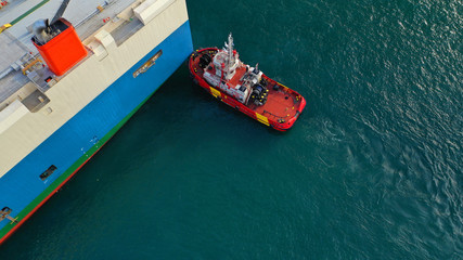 Aerial top down view of tug boat assist vessel pushing large tanker to position