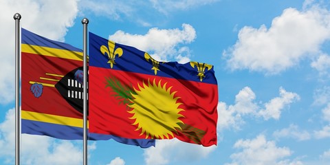 Swaziland and Guadeloupe flag waving in the wind against white cloudy blue sky together. Diplomacy concept, international relations.