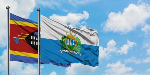 Swaziland and San Marino flag waving in the wind against white cloudy blue sky together. Diplomacy concept, international relations.