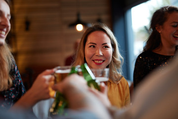 Friends standing in bar and toasting with beer.