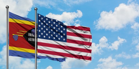 Swaziland and United States flag waving in the wind against white cloudy blue sky together. Diplomacy concept, international relations.