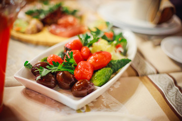 Plate with pickles - salty, saline tomatoes, pickles, corned onions and garnished with parsley. Cold appetizers in the restaurant at banquet in honor of holiday. New Year's table in Ukraine.