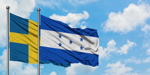 Sweden and Honduras flag waving in the wind against white cloudy blue sky together. Diplomacy concept, international relations.