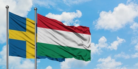 Sweden and Hungary flag waving in the wind against white cloudy blue sky together. Diplomacy concept, international relations.