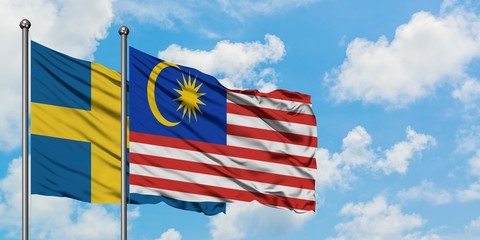 Sweden and Malaysia flag waving in the wind against white cloudy blue sky together. Diplomacy concept, international relations.