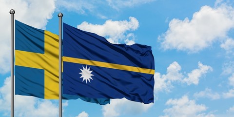 Fototapeta premium Sweden and Nauru flag waving in the wind against white cloudy blue sky together. Diplomacy concept, international relations.