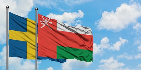Sweden and Oman flag waving in the wind against white cloudy blue sky together. Diplomacy concept, international relations.