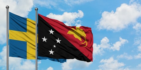 Sweden and Papua New Guinea flag waving in the wind against white cloudy blue sky together. Diplomacy concept, international relations.