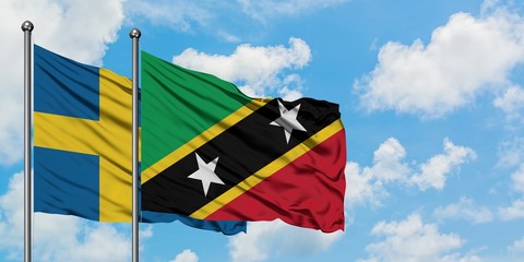 Sweden and Saint Kitts And Nevis flag waving in the wind against white cloudy blue sky together. Diplomacy concept, international relations.