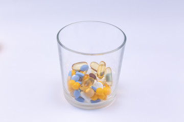 Dose of the colored pills in the glass of the package of pills. On white background with copy space for text
