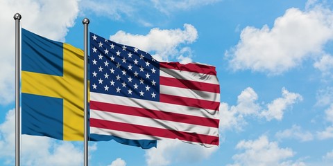 Sweden and United States flag waving in the wind against white cloudy blue sky together. Diplomacy concept, international relations.
