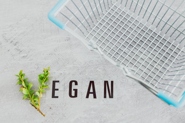 Vegan text with V made from small branches with leaves and shopping basket