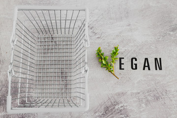 Vegan text with V made from small branches with leaves and shopping basket