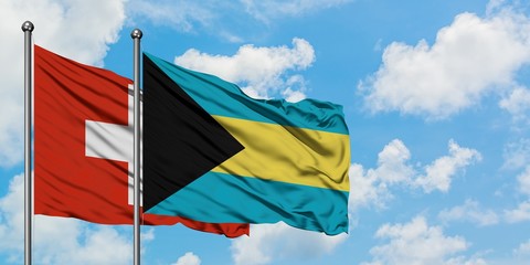 Switzerland and Bahamas flag waving in the wind against white cloudy blue sky together. Diplomacy concept, international relations.