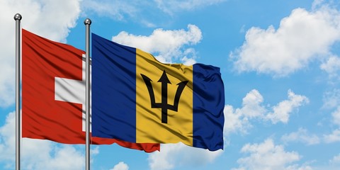 Switzerland and Barbados flag waving in the wind against white cloudy blue sky together. Diplomacy concept, international relations.