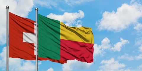 Switzerland and Benin flag waving in the wind against white cloudy blue sky together. Diplomacy concept, international relations.