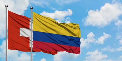 Switzerland and Colombia flag waving in the wind against white cloudy blue sky together. Diplomacy concept, international relations.