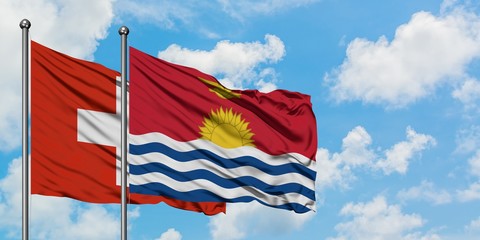 Switzerland and Kiribati flag waving in the wind against white cloudy blue sky together. Diplomacy concept, international relations.