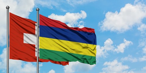 Switzerland and Mauritius flag waving in the wind against white cloudy blue sky together. Diplomacy concept, international relations.