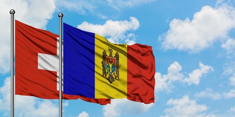 Switzerland and Moldova flag waving in the wind against white cloudy blue sky together. Diplomacy concept, international relations.