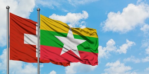 Switzerland and Myanmar flag waving in the wind against white cloudy blue sky together. Diplomacy concept, international relations.