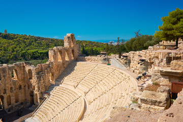 Fototapeta premium Panoramic image of ancient Greek theatre under Acropolis hill in Athens, Greece. Sunlit amphitheater on a sunny day with blue sky.