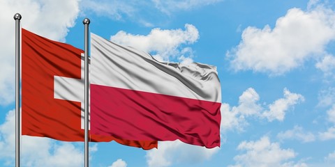Switzerland and Poland flag waving in the wind against white cloudy blue sky together. Diplomacy concept, international relations.