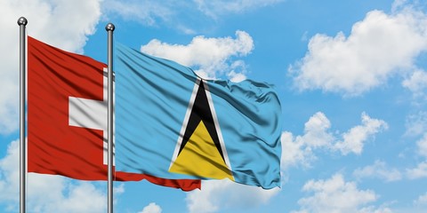 Switzerland and Saint Lucia flag waving in the wind against white cloudy blue sky together. Diplomacy concept, international relations.