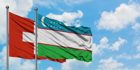 Switzerland and Uzbekistan flag waving in the wind against white cloudy blue sky together. Diplomacy concept, international relations.