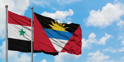 Syria and Antigua and Barbuda flag waving in the wind against white cloudy blue sky together. Diplomacy concept, international relations.