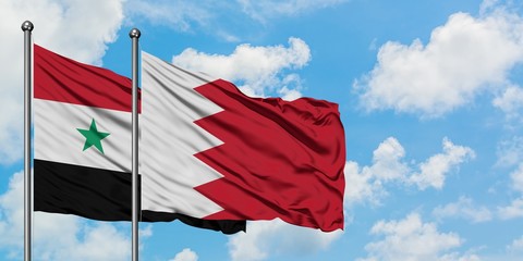 Syria and Bahrain flag waving in the wind against white cloudy blue sky together. Diplomacy...