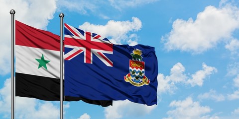 Syria and Cayman Islands flag waving in the wind against white cloudy blue sky together. Diplomacy...