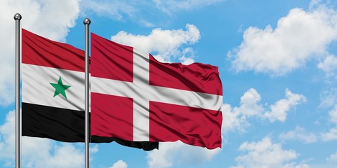Syria and Denmark flag waving in the wind against white cloudy blue sky together. Diplomacy...