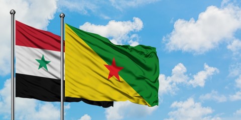 Syria and French Guiana flag waving in the wind against white cloudy blue sky together. Diplomacy concept, international relations.