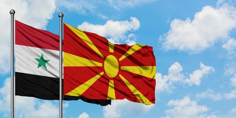 Syria and Macedonia flag waving in the wind against white cloudy blue sky together. Diplomacy...