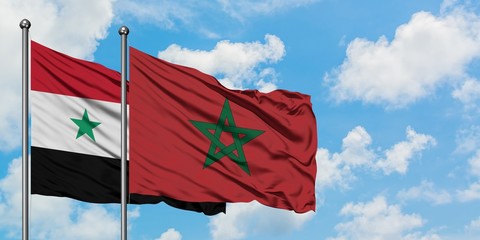 Syria and Morocco flag waving in the wind against white cloudy blue sky together. Diplomacy...
